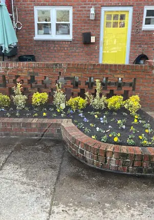 Brick front-yard planter with fresh flowers outside a Brooklyn rowhouse