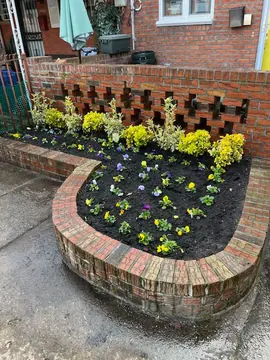 Curved brick planter filled with fresh flowers in Brooklyn